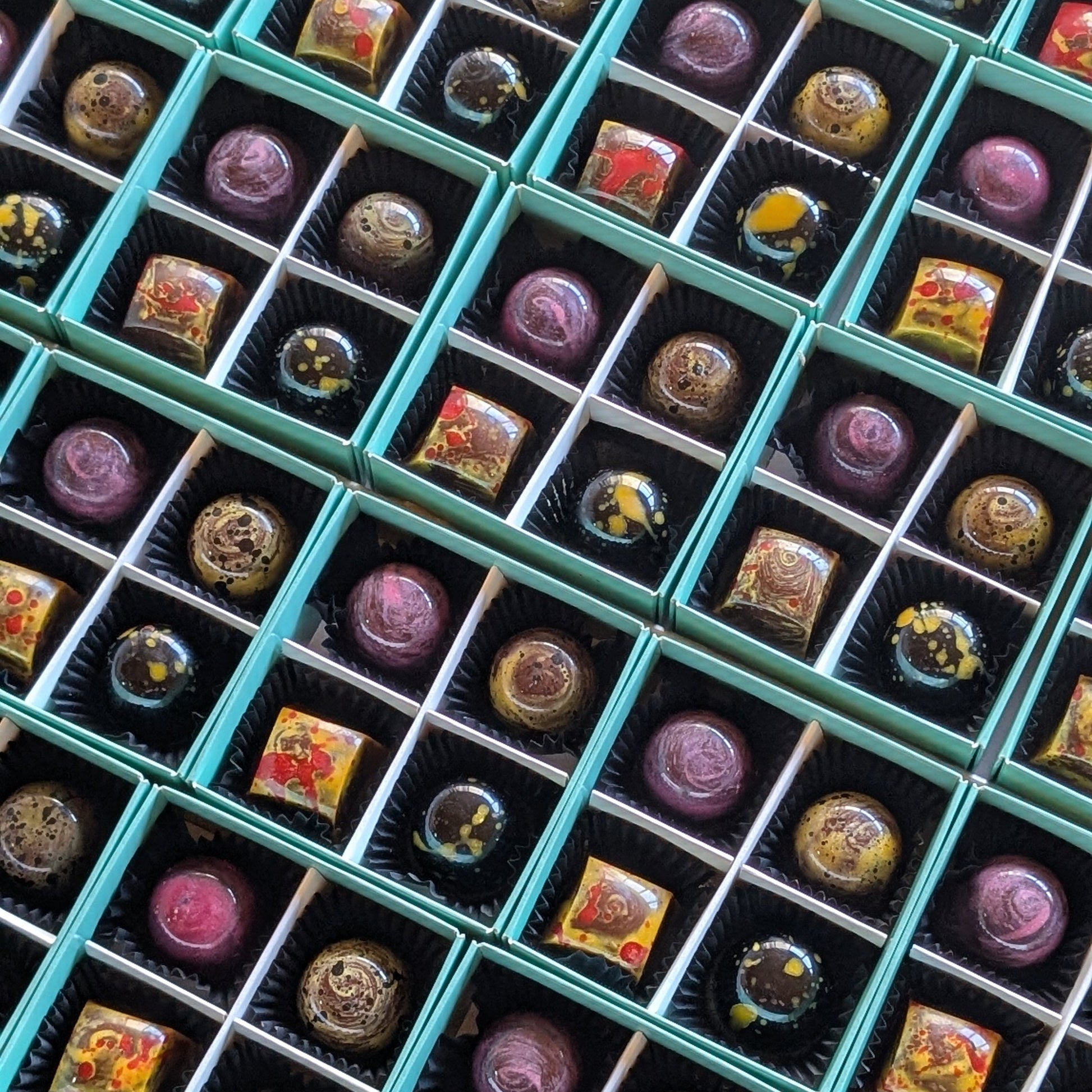 Assorted handmade chocolate bonbons in teal gift boxes